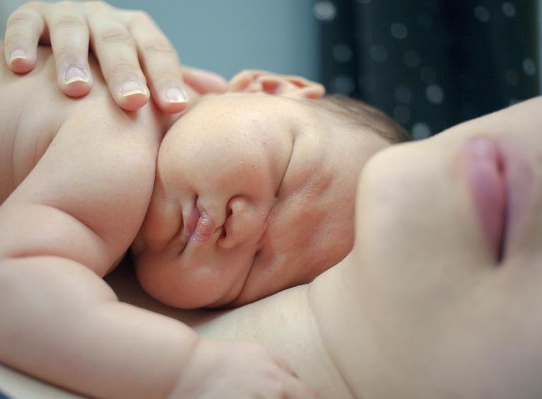 Newborn baby laid with mother