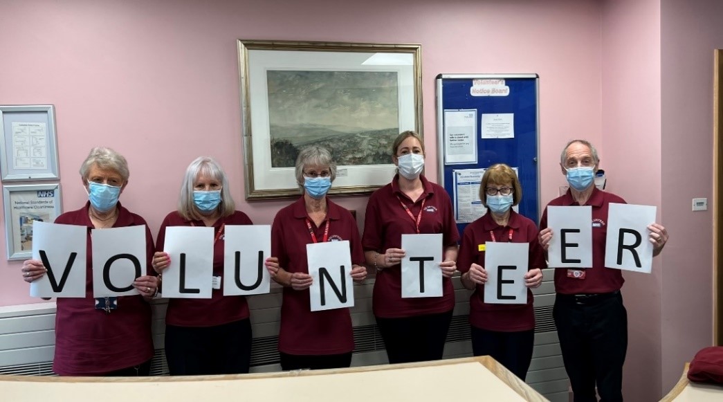 A group of volunteers holding up letters to spell the word "Volunteer"