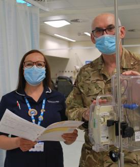 Two nurses stand next to each other. One wears a military uniform