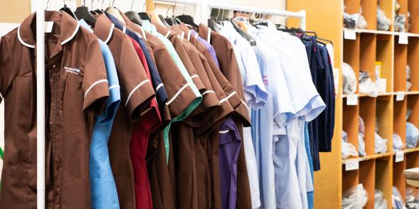 A selection of nursing and care staff uniforms hanging on a clothes rail 