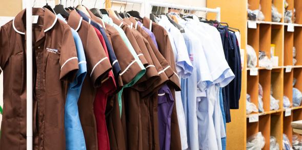 A selection of nursing and care staff uniforms hanging on a clothes rail