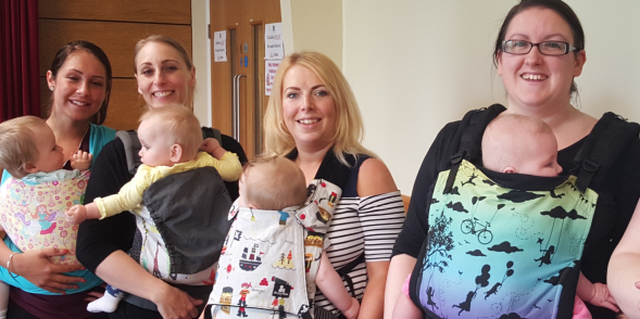 A group of mum's using baby slings to carry their children