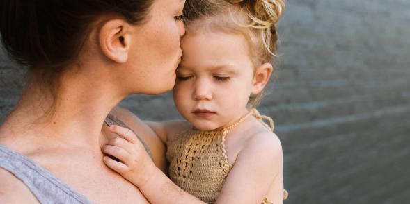 A mum kisses her child on the forehead