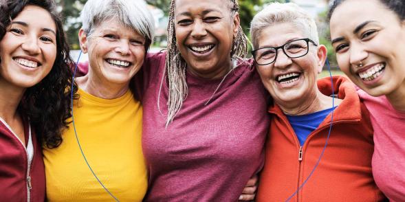 Five women standing shoulder to shoulder, smiling at the viewer