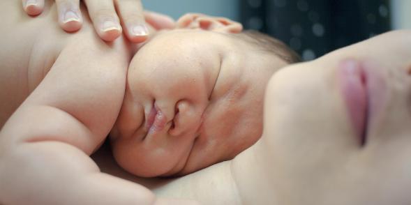 Baby lies sleeping on mum's chest 