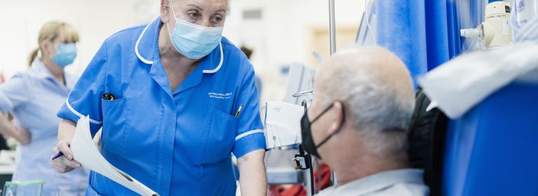 A nurse speaks to a patient who is seated