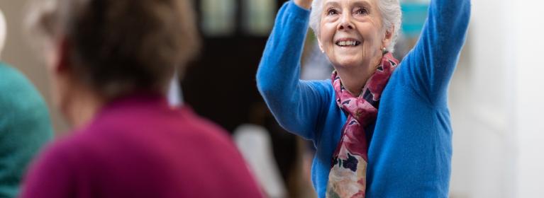 An older woman dances whilst smiling 