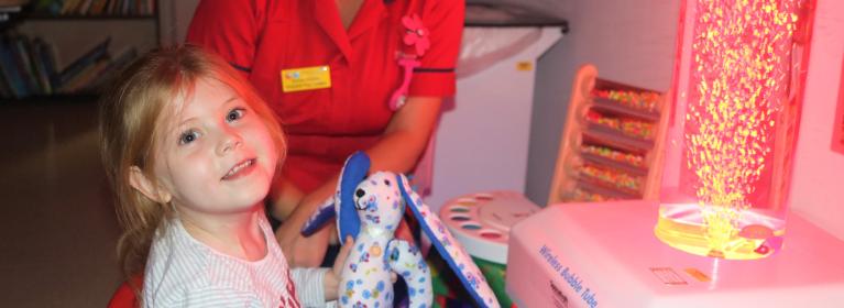 Hospital staff passes a stuffed toy to a young patient
