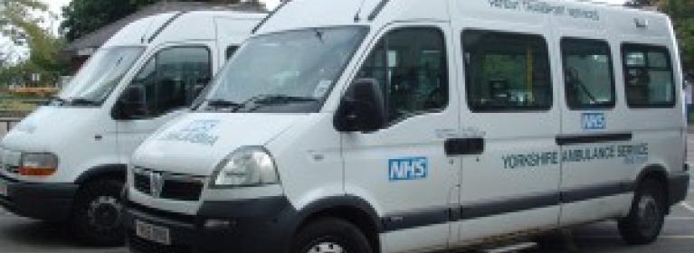 Two white mini-buses used for patient transport, to and from Barnsley Hospital - the NHS logo and Yorkshire Ambulance Service is written on the buses.