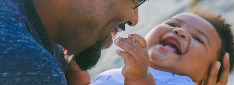A happy father holds his laughing baby