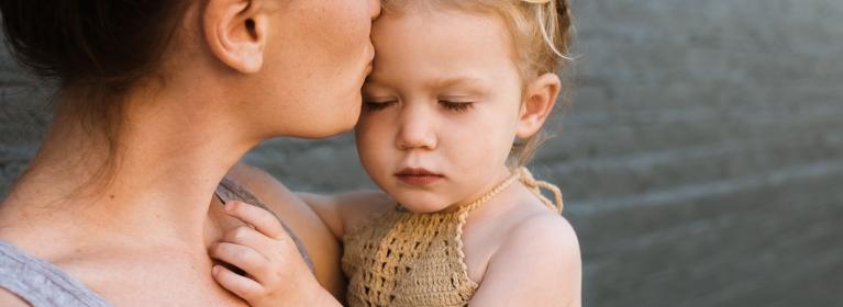 A mum kisses her child on the forehead