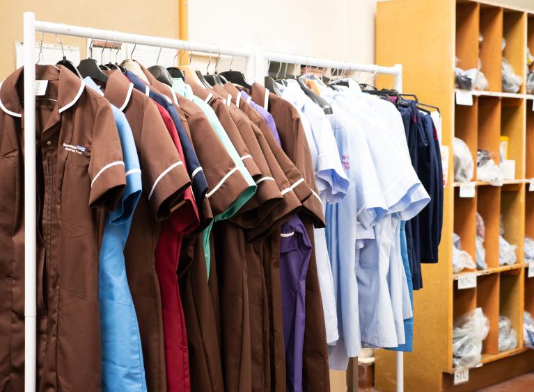 A selection of nursing and care staff uniforms hanging on a clothes rail 