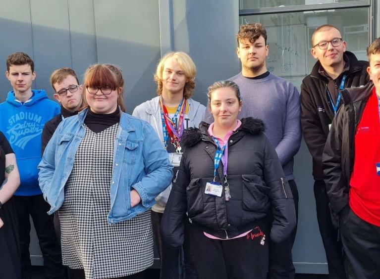 9 students from Barnsley College proudly stand together; they are all disabled and have started work placements at Barnsley Hospital via a scheme run by Project Search.