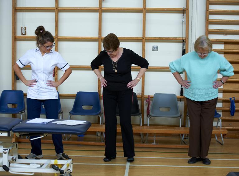 A nurse guides two people who are older than 50 through an exercise routine