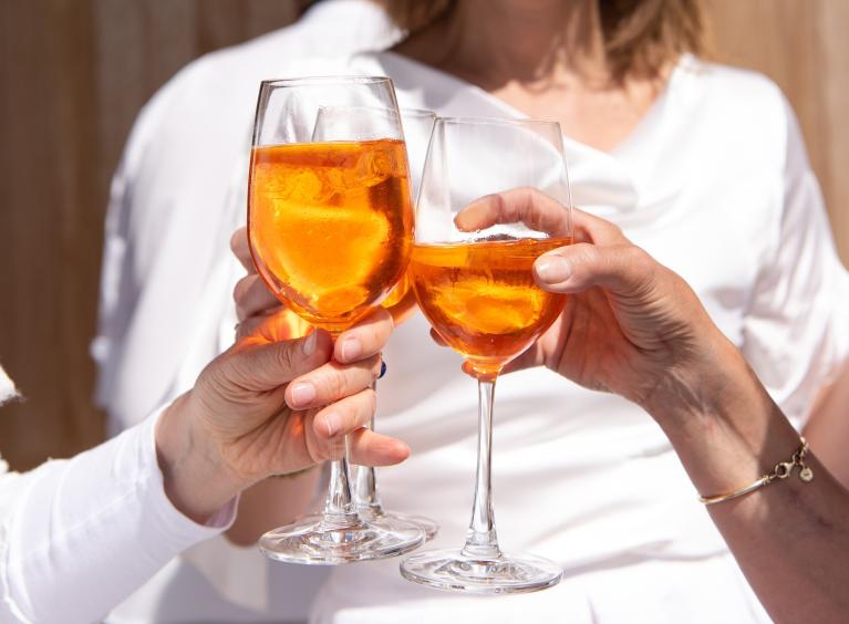 Three people share a toast with three glasses of alcohol