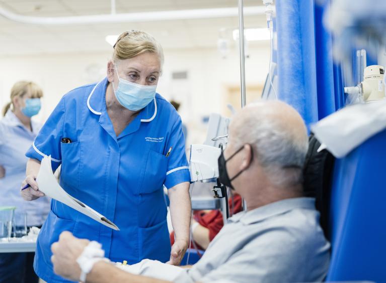 A nurse speaks to a patient who is seated