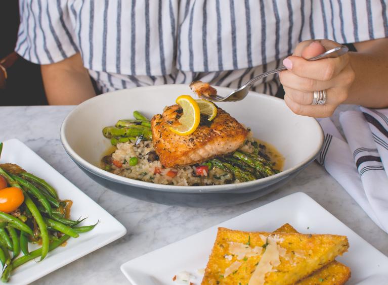 A person is eating a meal; salmon and rice and vegetables with a side salad and toast.