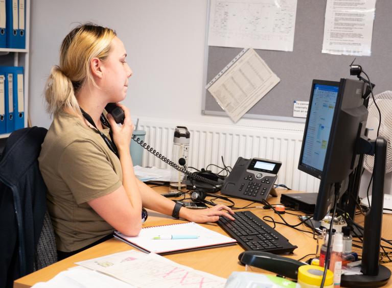 A receptionist talks on the phone to a patient.