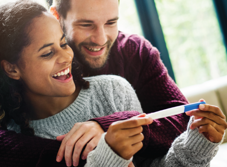 A couple look at a pregnancy test with delight