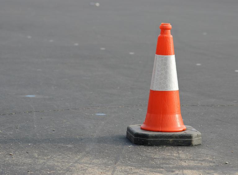 A single traffic cone on a tarmac surface