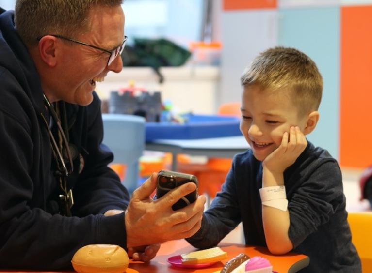 A doctor talks to a child, showing them the screen of a mobile phone