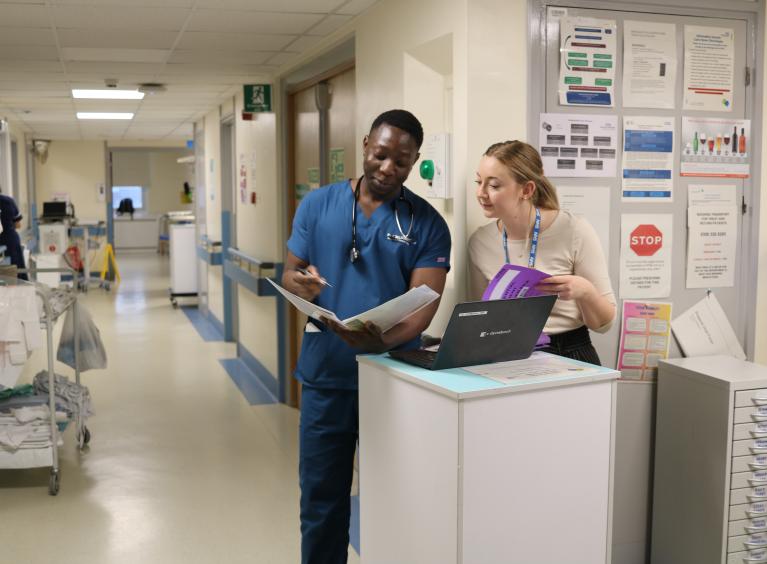 Colleagues review a document on a ward