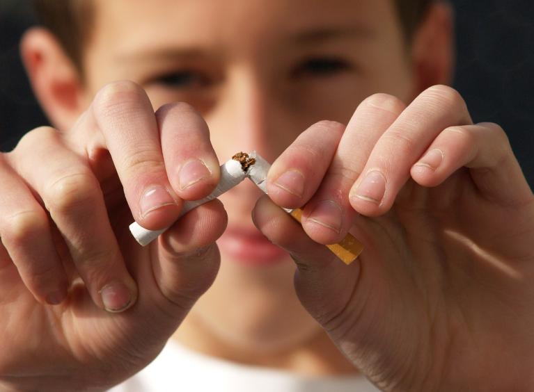 Young boy breaking a cigarette in half