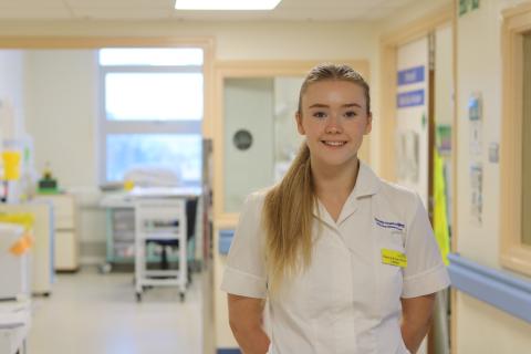 An Intensive Care Unit Dietician smiles whilst standing in a hospital corridor 
