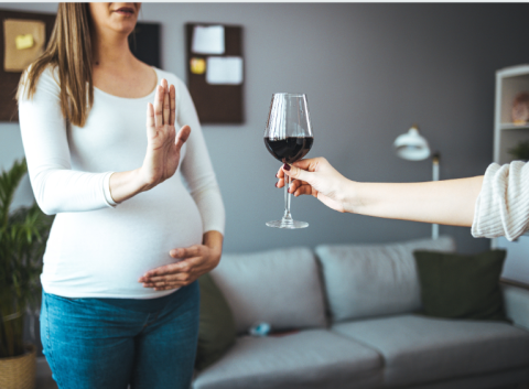 A pregnant woman refuses a glass of wine